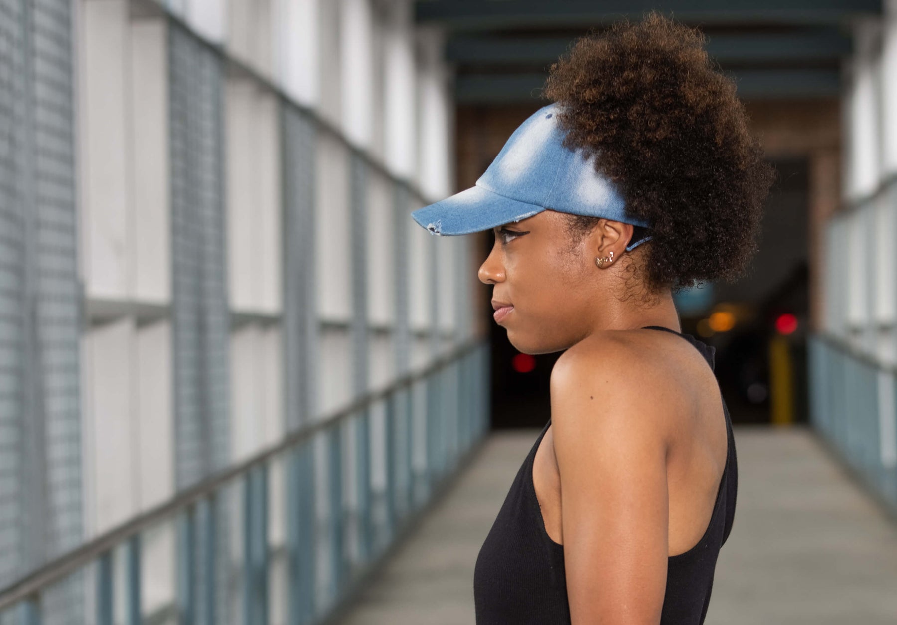 Black woman with puff wearing a backless satin lined denim hat by beautifully warm